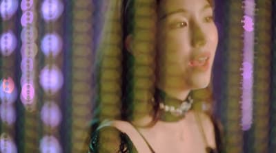 a woman in a green dress standing in front of a curtain