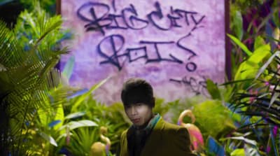 a man standing in a jungle with a sign in the background