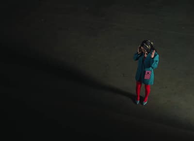 a little girl standing in the dark talking on a cell phone