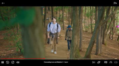 a man and a woman walking through a forest