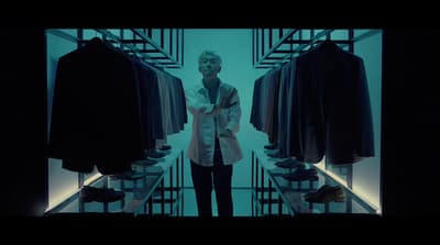 a man standing in front of a rack of shirts
