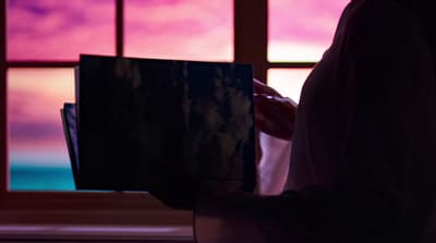 a person holding a book in front of a window