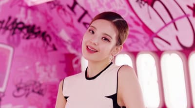 a woman standing in front of a pink wall