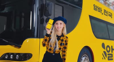 a woman standing in front of a yellow bus