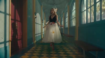 a woman in a dress walking down a hallway