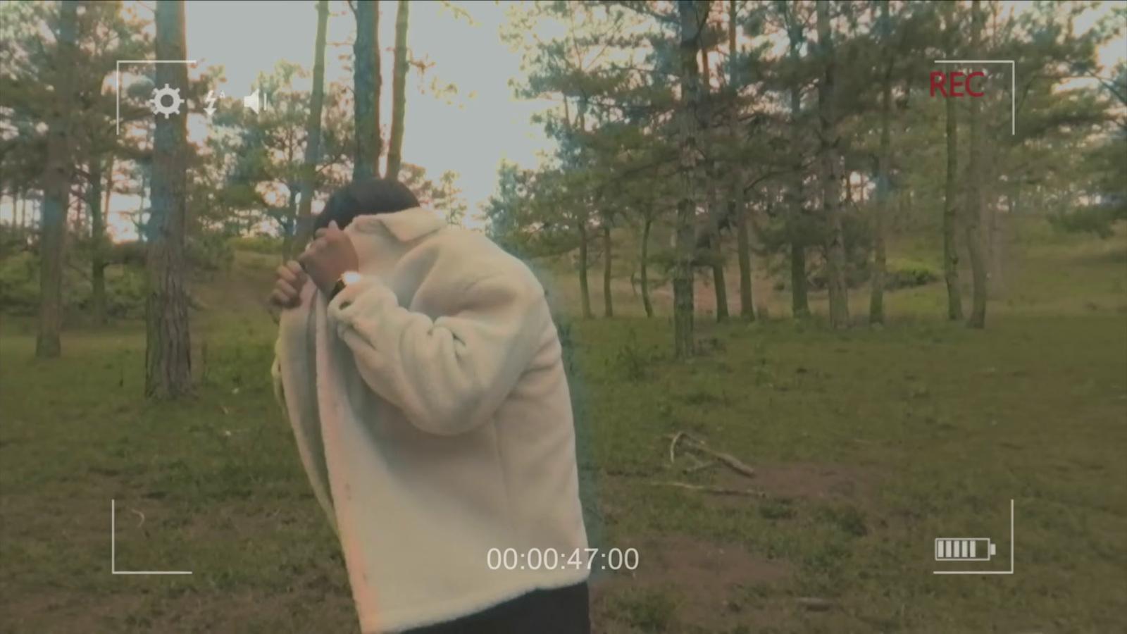 a man standing in a forest holding a camera
