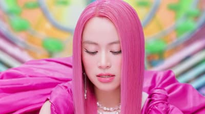 a woman with pink hair and a pearl necklace