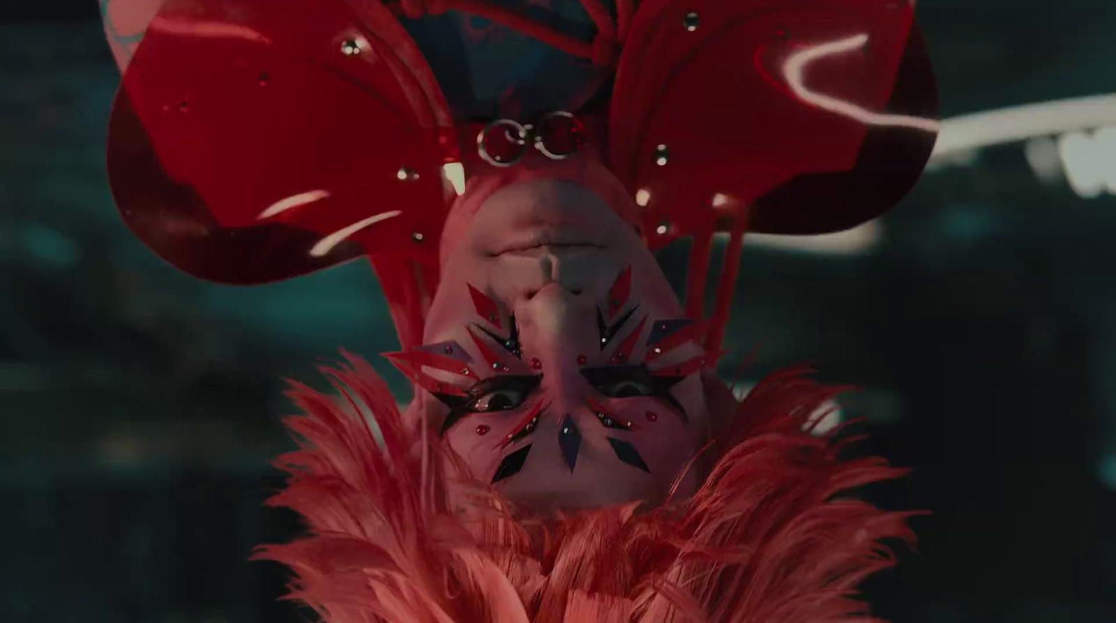 a woman wearing a red mask with feathers on her head