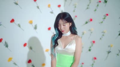 a woman in a green and white dress standing in front of a flower wall