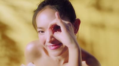 a woman smiling and holding her hand to her face