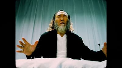 a man with long hair and a beard sitting in a chair