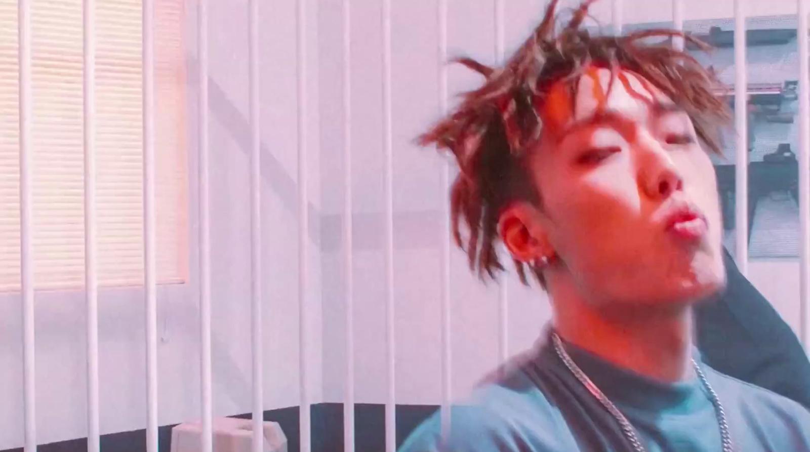 a man with dreadlocks standing in front of a window