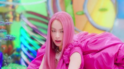 a woman with pink hair is laying on the ground
