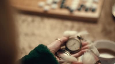a close up of a person holding a clock