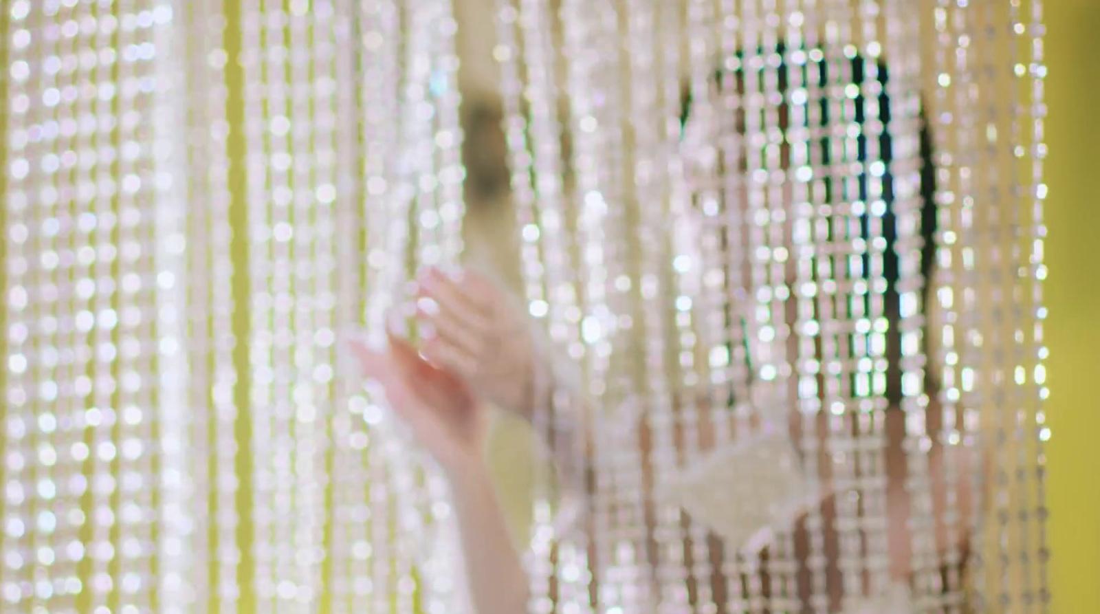 a woman standing in front of a window covered in beads