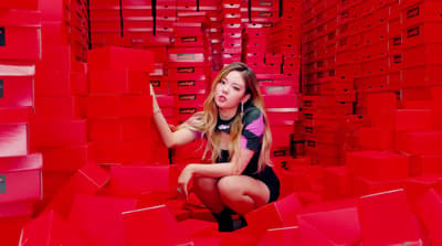 a woman kneeling down in a room full of red boxes
