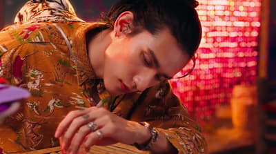 a man in a kimono looking down at a piece of wood