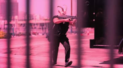 a man holding a gun behind a fence