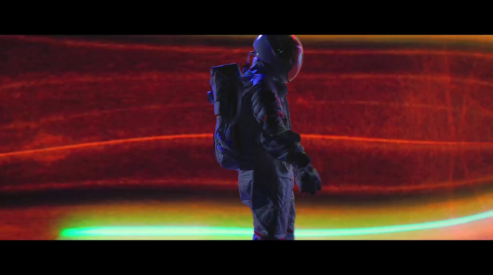 a man with a backpack standing in front of a red background