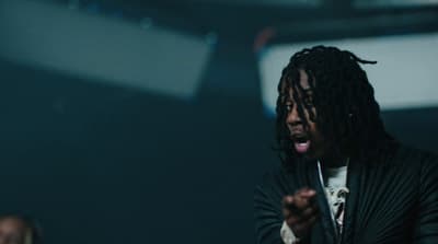a man with dreadlocks standing in a dark room