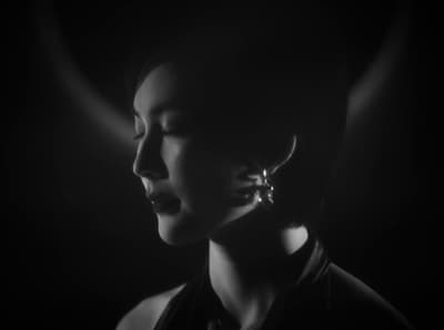 a woman in a black dress with a pair of earrings on her ear