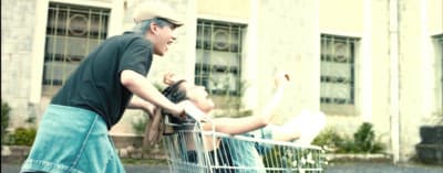 a man pushing a woman in a shopping cart