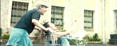 a man pushing a woman in a shopping cart