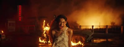 a woman standing in front of a fire with her mouth open