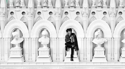 a person sitting on a ledge in front of a building