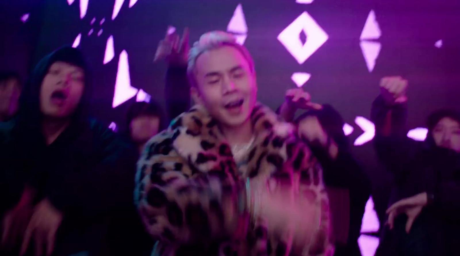 a man in a leopard print coat singing into a microphone