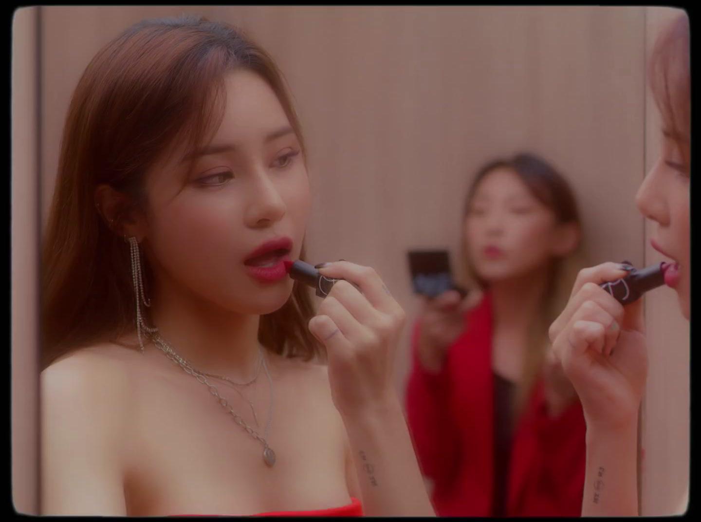 a woman putting lipstick on another woman's face