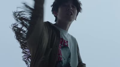 a young man standing next to a tall palm tree