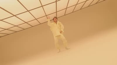a man in a white suit standing in a room