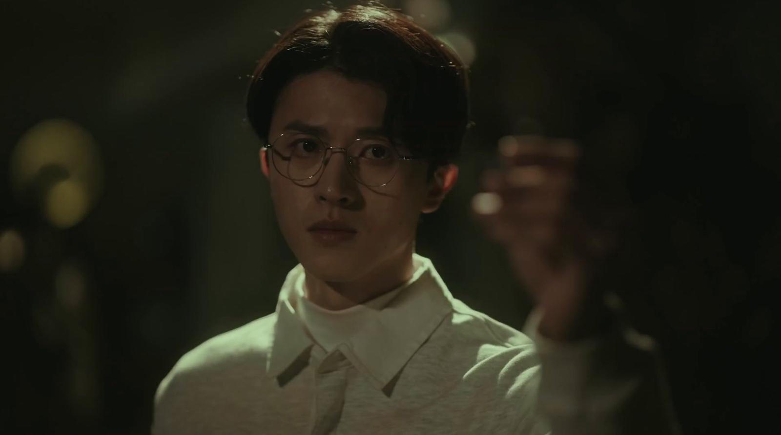 a young man wearing glasses holding a wine glass