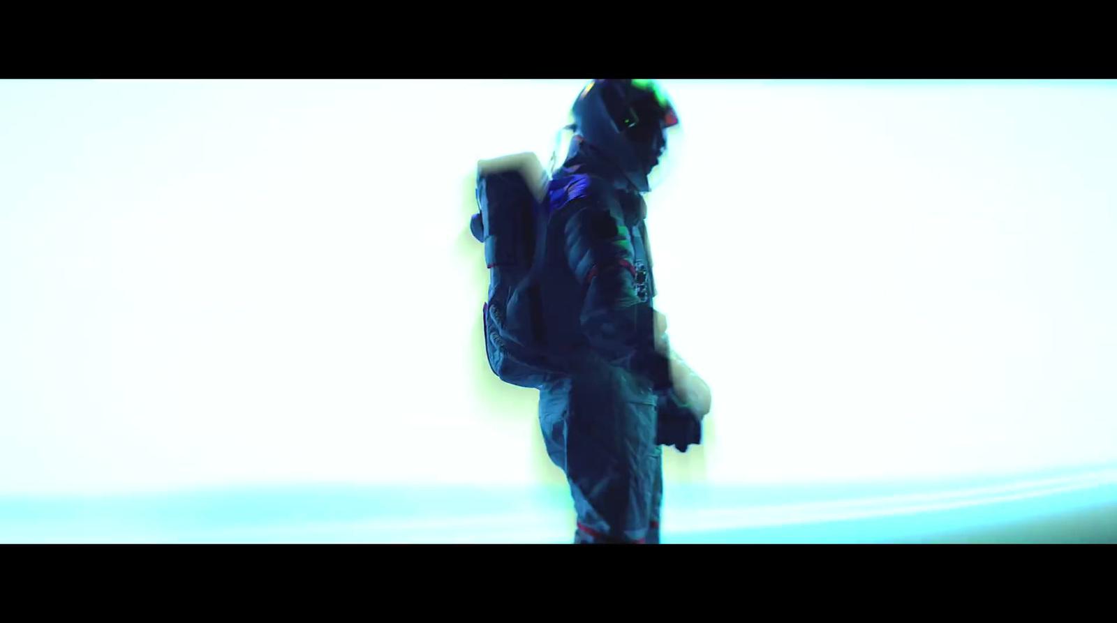 a man with a backpack is standing in front of a white wall