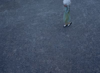 a little girl walking across a street holding an umbrella