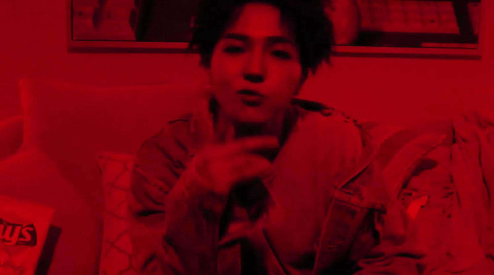 a man sitting on a couch in a room with red light