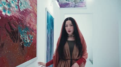 a woman standing in a hallway next to a painting