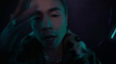 a man in a dark room holding his hand up to his face