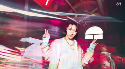 a man standing in front of a window holding a peace sign