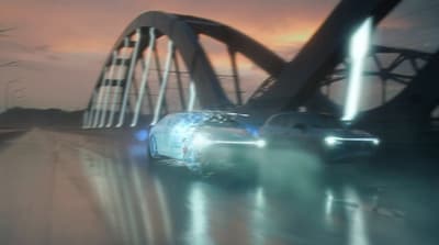 a couple of cars driving down a street next to a bridge