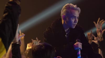 a man holding a microphone in front of a crowd of people