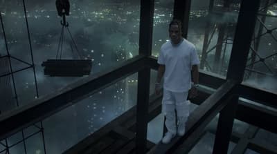a man in a white shirt and white pants standing on a balcony