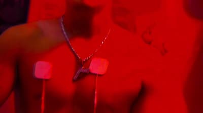 a shirtless man wearing headphones in a red room