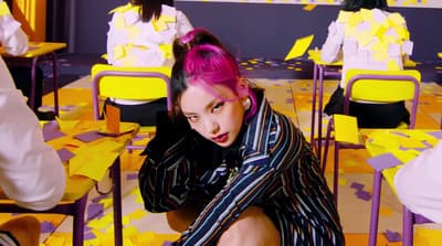 a woman with pink hair sitting on a chair