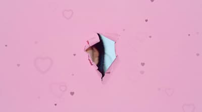 a hole in a pink paper with hearts on it