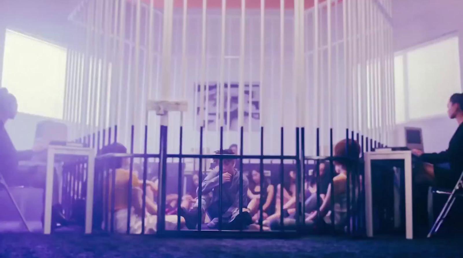 a group of people sitting in a room behind a fence