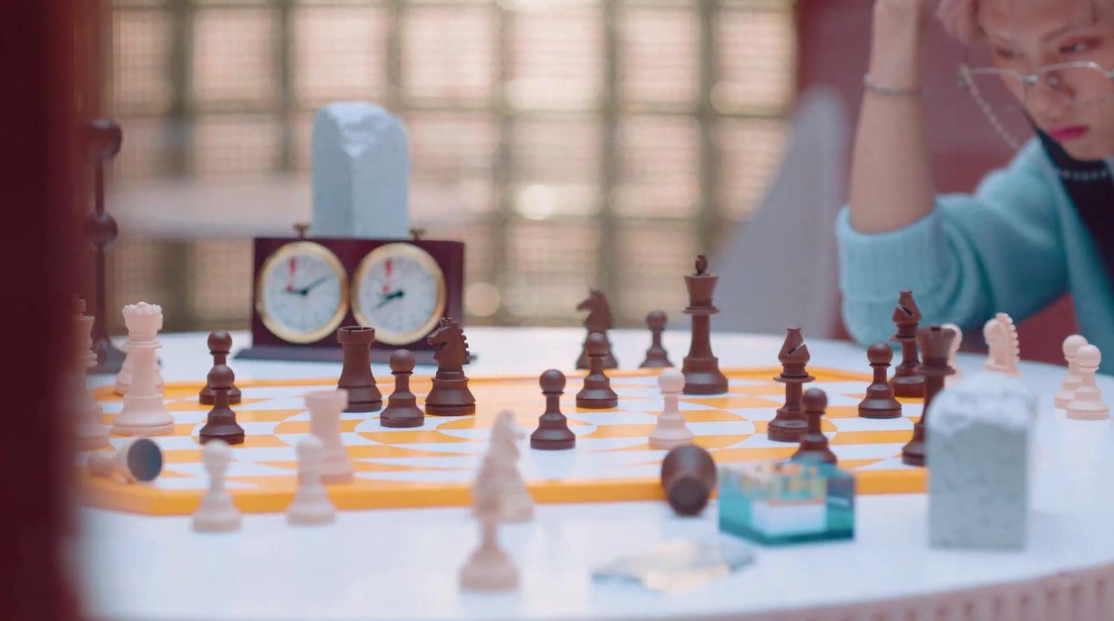 a woman sitting at a table with a chess set