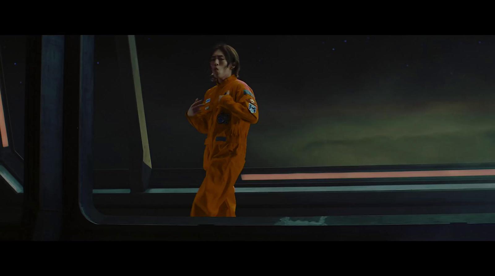 a man in an orange space suit standing in front of a window
