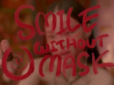 a woman holding up a sign that says smile without a mask